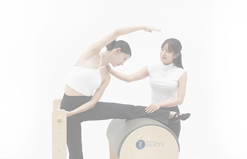 필라테스 기구 위에서 회원의 자세를 지도하는 강사